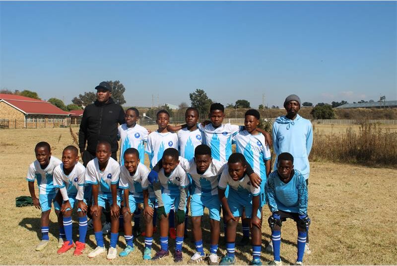 Group of young football players wearing white and turquoise strips