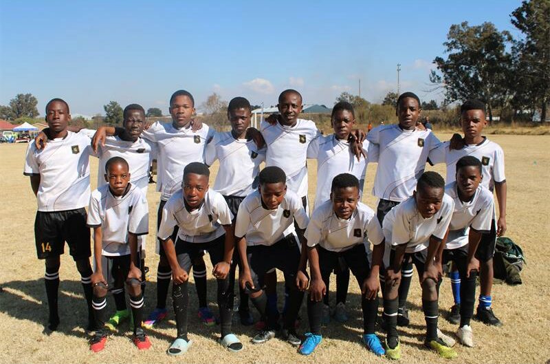 Group of young black football players wearing white and black strips