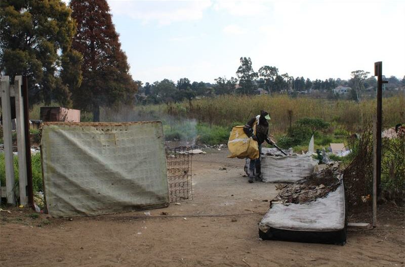 Make shift gate made with matrasses and man walking with a bag over his shoulders