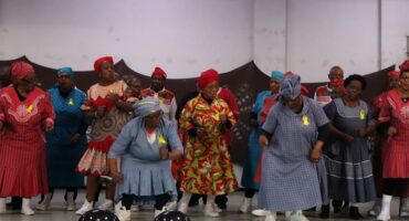 Black women in colourful attire dancing on stage