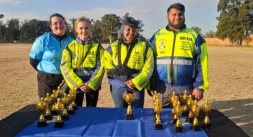 Four people standing behind a table with trophies
