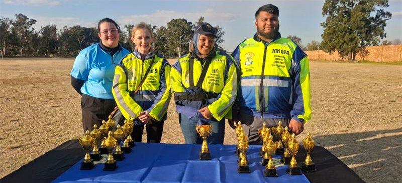 Four people standing behind a table with trophies