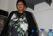 Indian woman balances on a crutch standing next to bottles of water