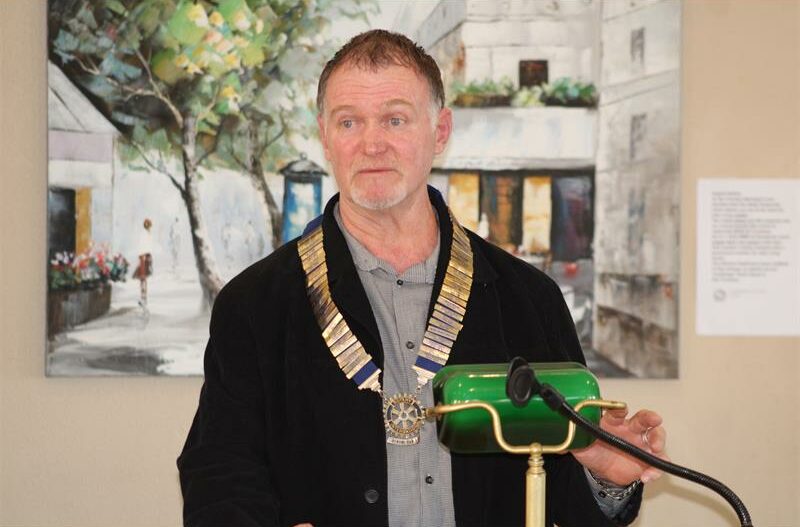 Man wearing a Rotary president's chain standing behind a podium