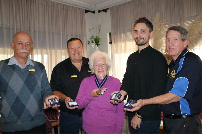 Group of five people, four men and one woman holding medals of honour