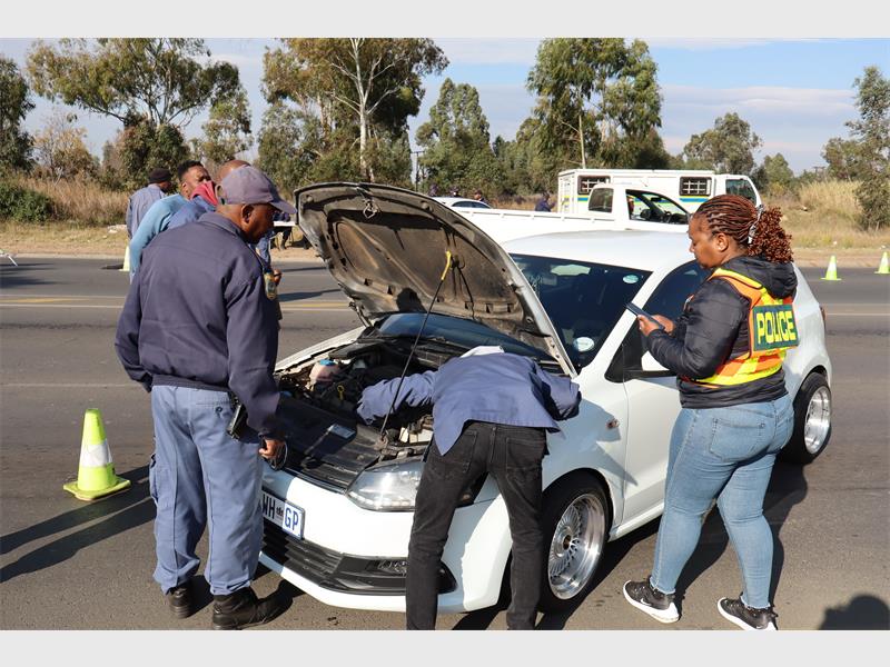 Police officers examine the engine of a car during an operation.