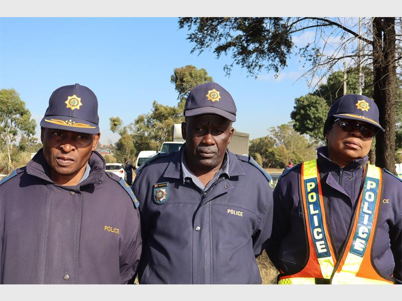 Three black police officers standing for a photograph during an operation.