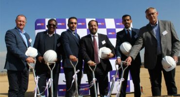 Group of multi-cultural men holding white hard hats and shovels