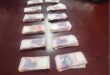 R19 500 in cash laid out in piles next to each other on a wooden table.