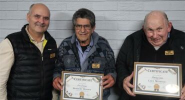 Two men holding certificated standing next to a bald man