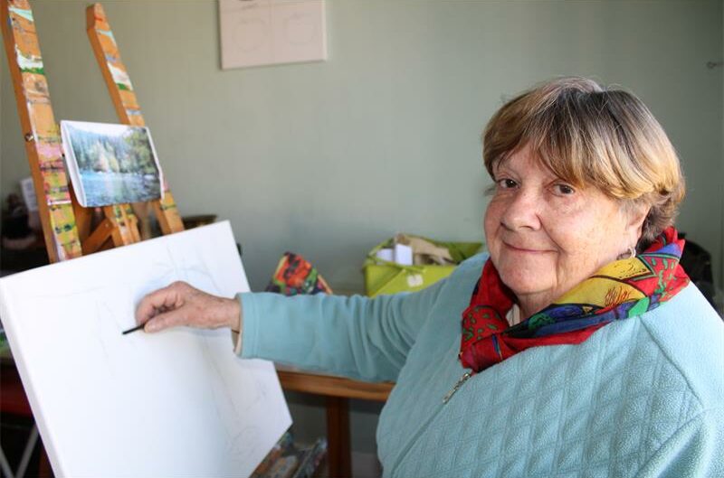 Elderly woman drawing on a canvas.