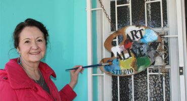 Woman stands holding a paint brush