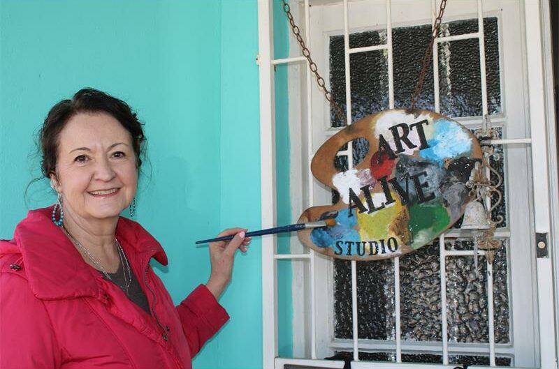 Woman stands holding a paint brush