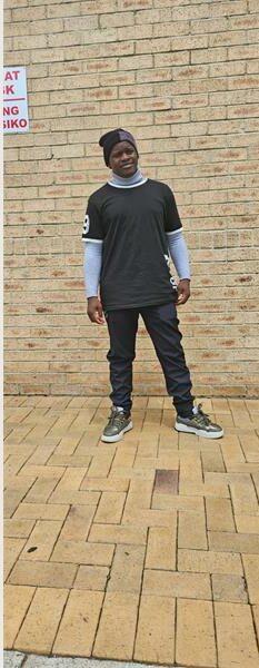 Black man standing in front of a brick wall