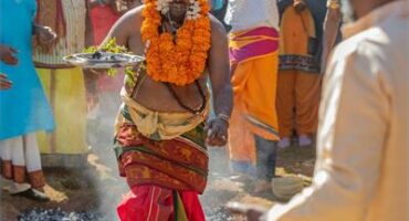 Man in traditional attire walking over coals