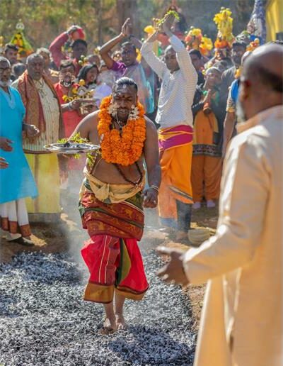 Man in traditional attire walking over coals