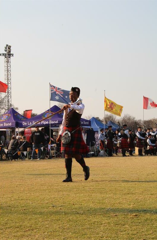 Black girl wearing a kilt marching with a mace