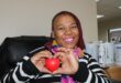 Black woman smiling while holding a red heart