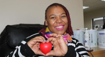 Black woman smiling while holding a red heart