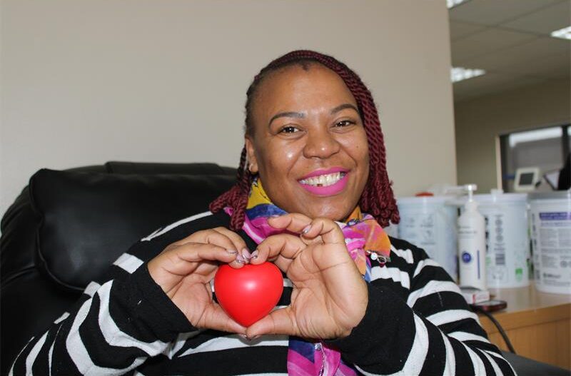 Black woman smiling while holding a red heart