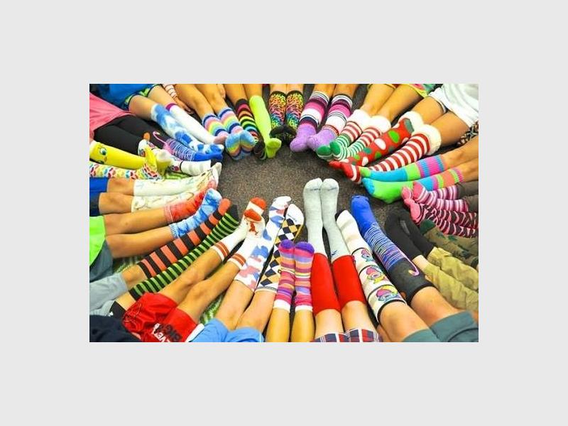 Children's legs together in a circle all wearing long colourful socks.