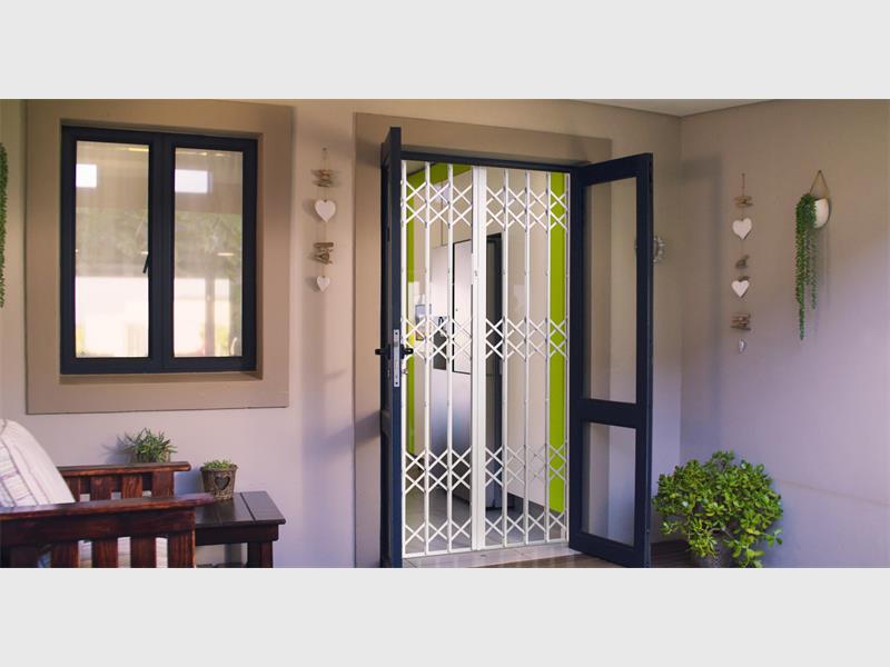 A view of double glass doors taken from inside showing a security gate protecting the home.