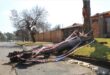 Image of a large tree branch laying across the road with caution tape surrounding it