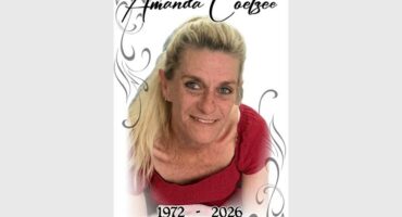 A blonde woman dressed in a red dress taken from above with the words Amanda Coetzee above her head.