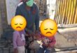 Elderly woman holding two children whose faces are blocked with an emoji