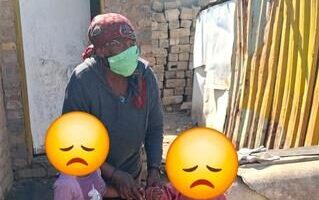 Elderly woman holding two children whose faces are blocked with an emoji
