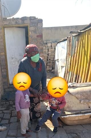 Elderly woman holding two children whose faces are blocked with an emoji