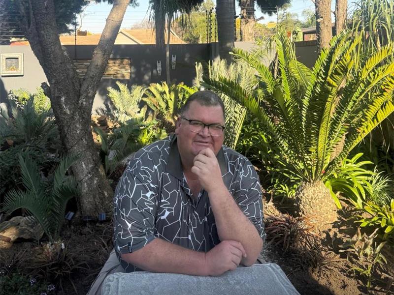 Man sitting at a concrete table with cycads in the background