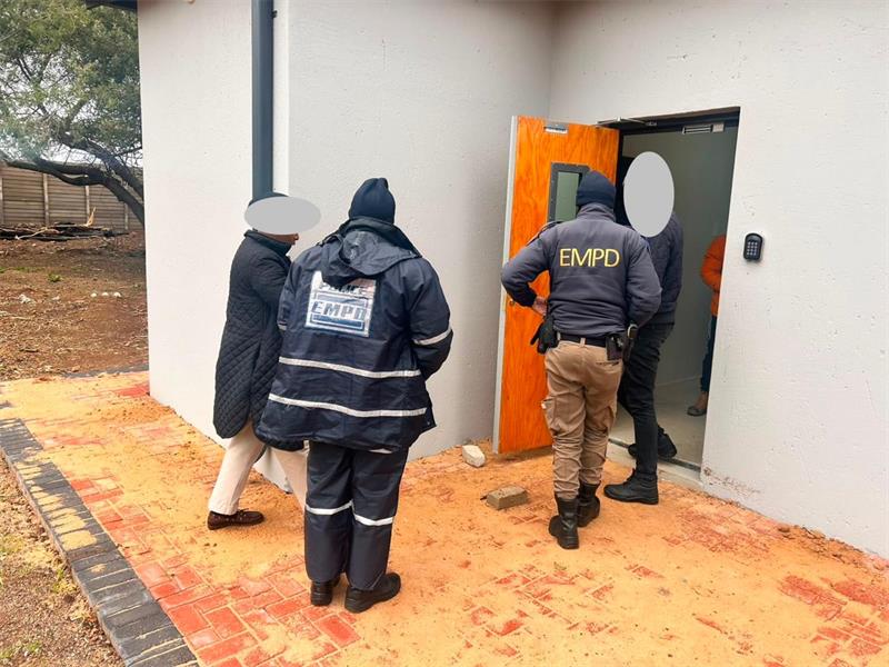 Three people two of which are wearing EMPD uniforms walking into a door