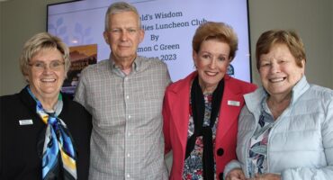 Three women smiling standing next to a man