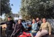 Two men standing next to a quad bike with three women sitting on top
