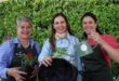 Three women posing with plants, a watering can and hanging basket