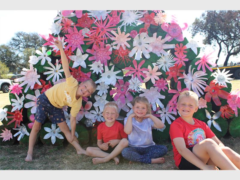 Four kids, a girl and three boys doing playful poses in front of a spring display