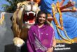 Indian woman wearing a purple sari sitting in front of a religious statue