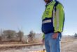 Man wearing a reflective jacket standing at a pothole