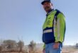 Man wearing a reflective jacket standing at a pothole