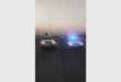 Two vehicles with headlights on facing the camera and parked on a highway.