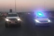 Two vehicles with headlights on facing the camera and parked on a highway.