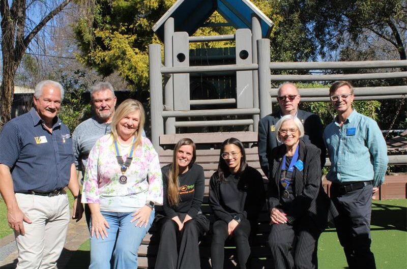 Group of people standing next to or sitting on a jungle gym
