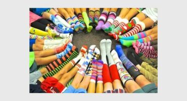 Legs wearing colourful socks facing inwards to form a circle.