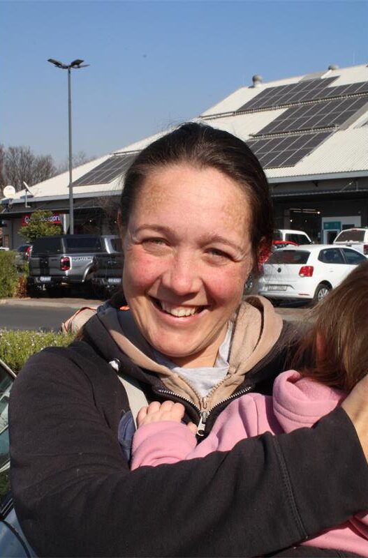 White woman smiling and holding a child