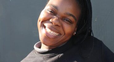 Black woman smiles as she makes a playful pose
