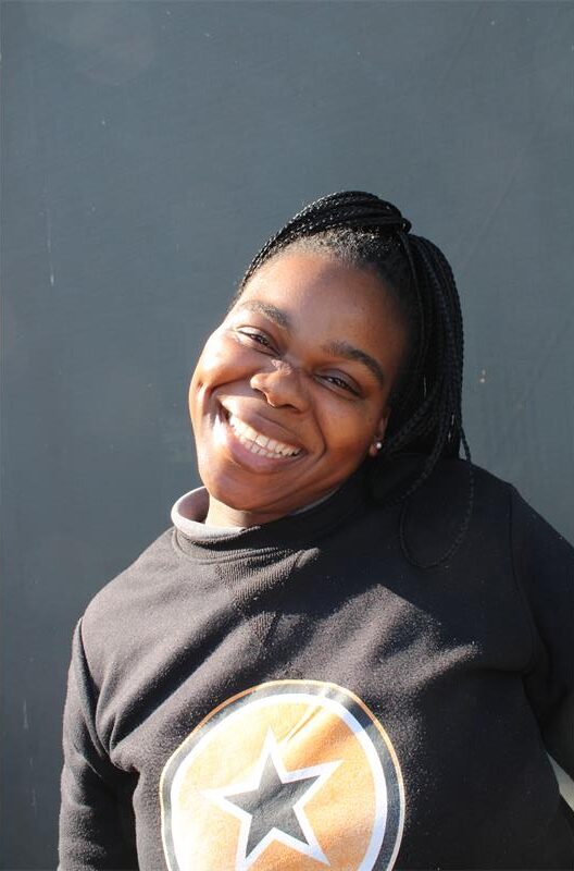 Black woman smiles as she makes a playful pose