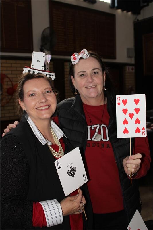 Two white women smile while holding big playing cards