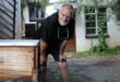 Older man looking at a beehive