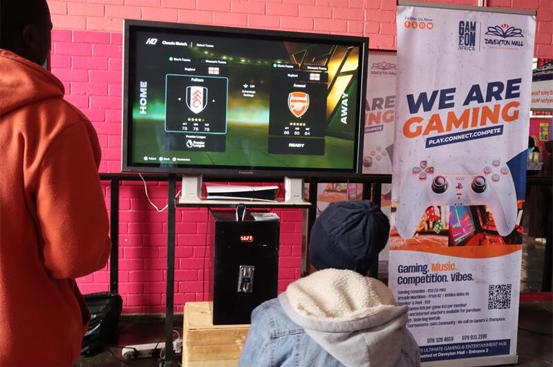 Two males facing the opposite direction playing tv games 